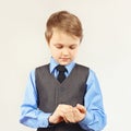 Little stylish boy fastened the buttons on sleeve blue shirt