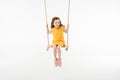Little stylish child in dress riding on swing