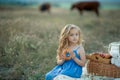 Little stylish kid wearing trendy checked shirt and jeans is having fun on the picnic. He is drinking yogurt and has