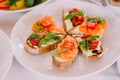 Little stylish sandwiches with red fish and tomatoes. Fish snack for the holiday table. Elegant canapes and salmon