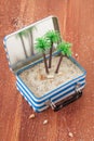 Little suitcase with sand and palm trees