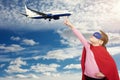 Little super hero girl holds an airplane with her finger