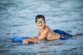 Little surfer learn to ride on surfboard on sea wave. Kid play in summer ocean, learning surfing, riding a wave. Little boy swim Royalty Free Stock Photo