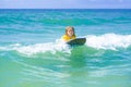 Little surfer learn to ride on surfboard on sea wave. Kid play in summer sea. Kid girl is learning surfing, riding a Royalty Free Stock Photo