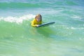 Little surfer learn to ride on surfboard on sea wave. Summer vacation with child. Kid girl is learning surfing, riding a Royalty Free Stock Photo