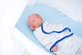 Little swaddled baby in white bed