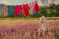 Little sweet baby sitting on wooden box in lavender field and posing for camera. Colorful clothes hanging on rope in Royalty Free Stock Photo