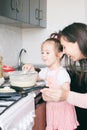 Little sweet girl and her mother fry pancakes at the traditional Russian holiday Carnival Maslenitsa Shrovetide Royalty Free Stock Photo