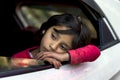 Little sweet girl tired and resting on window ledge of moving white car at Himachal Pradesh.