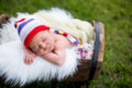 Little sweet newborn baby boy, sleeping in crate with knitted pa Royalty Free Stock Photo