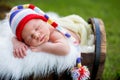 Little sweet newborn baby boy, sleeping in crate with knitted pants and hat in garden Royalty Free Stock Photo