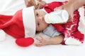 Little sweet newborn baby girl with Christmas sweater and Santa hat on white warm bed, portrait of adorable infant with her mom Royalty Free Stock Photo