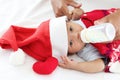 Little sweet newborn baby girl with Christmas sweater and Santa hat on white warm bed, portrait of adorable infant with her mom Royalty Free Stock Photo