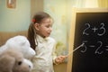 Little teacher. Beautiful young girl is teaching toys at home on Royalty Free Stock Photo