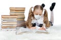 Little teen girl in medical mask lie home and read big textbook