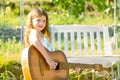 Little teen girl musician playing guitar. Dreamy kids face. Smiling child playing outdoors in summer. Royalty Free Stock Photo