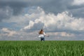 little teenager girl running in a field of green grass, against the backdrop of a cloudy sky Royalty Free Stock Photo