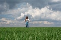 little teenager girl running in a field of green grass, against the backdrop of a cloudy sky Royalty Free Stock Photo