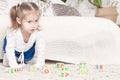 A little three-year-old girl plays cubes on which letters and numbers are drawn Royalty Free Stock Photo