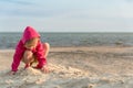 Little three years old girl playing in the sand on the sea beach, sunset and little breeze and , summer vacation, child developmen Royalty Free Stock Photo