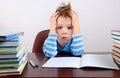 Little tired boy sitting at a desk and holding hands to head Royalty Free Stock Photo