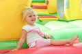 A little tired girl sits on a children`s inflatable trampoline in an amusement park Royalty Free Stock Photo