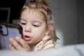 Little toddle girl playing with smartphone laying on the bed at home. Caucasian toddler girl.