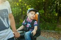 Little toddler boy in a baseball cap on bike seat cycling with father in nature. Royalty Free Stock Photo