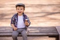 Little toddler boy in checkered shirt and cap sitting on bench, eating ice-cream and enjoying the life in spring or summer day Royalty Free Stock Photo