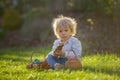 Little toddler boy, eating chocolate bunny in garden on sunset, easter eggs Royalty Free Stock Photo