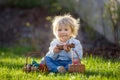 Little toddler boy, eating chocolate bunny in garden on sunset, easter eggs Royalty Free Stock Photo