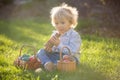 Little toddler boy, eating chocolate bunny in garden on sunset, easter eggs Royalty Free Stock Photo