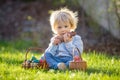 Little toddler boy, eating chocolate bunny in garden on sunset, easter eggs Royalty Free Stock Photo