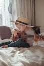 Little toddler boy in hat playing ukulele guitar at home, rustic style. Lifestyle concept Royalty Free Stock Photo