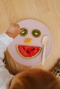 Little toddler boy and imrovised fruit face dinner on a plate Royalty Free Stock Photo