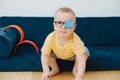 Little toddler boy in lazy eye patch is playing with toy cars