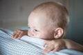 Little toddler boy playing on the bed. Cute kid smiling and hiding under cover. Palyful and mischievous eyes. Hide-and-seek. Royalty Free Stock Photo