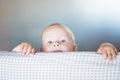 Little toddler boy playing on the bed. Cute kid smiling and hiding under cover. Palyful and mischievous eyes. Hide-and-seek. Royalty Free Stock Photo
