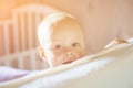 Little toddler boy playing on the bed. Cute kid smiling and hiding under cover. Palyful and mischievous eyes. Hide-and-seek. Royalty Free Stock Photo