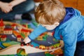 Little toddler boy playing with wooden railway, indoors. Happy cute child moving trains at home or daycare. Lifestyle Royalty Free Stock Photo