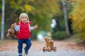 Little toddler boy with teddy bear, riding wooden dog balance bi Royalty Free Stock Photo