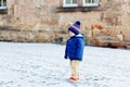 Little toddler boy walking through the snowy city during snowfall. Cute happy child in winter clothes having fun Royalty Free Stock Photo