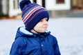 Little toddler boy walking through the snowy city during snowfall. Cute happy child in winter clothes having fun Royalty Free Stock Photo