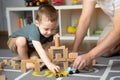 Little toddler boy 2,5 years playing wooden blocks and toy cars with dad. Royalty Free Stock Photo