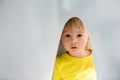 Little toddler boy with yellow shirt, hiding under blanket, smiling Royalty Free Stock Photo