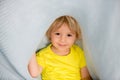 Little toddler boy with yellow shirt, hiding under blanket, smiling Royalty Free Stock Photo