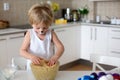 Little toddler child, blond boy with painted face as a rabbit, preparing dough for brioche buns for easter