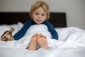 Little toddler child feet on the foreground, cute child, lying in bed, playing with little stuff toy Royalty Free Stock Photo