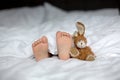 Little toddler child feet on the foreground, cute child, lying in bed, playing with little toy Royalty Free Stock Photo