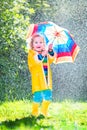 Little toddler with colorful umbrella playing in rain Royalty Free Stock Photo